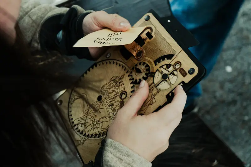 Ruce otevírají dřevěný šifrovací mechanismus s ozubenými koly - prop Scavenger Hunt Prague