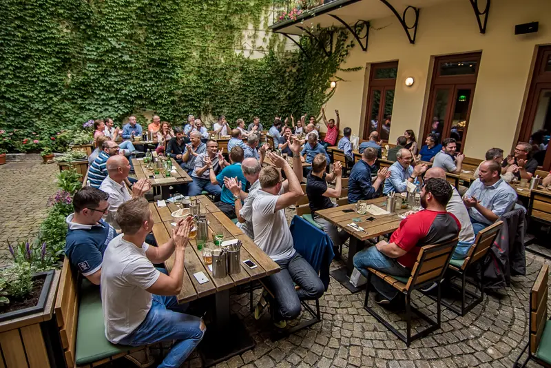 Velká skupina firemního teambuildingu v zahradní restauraci v Praze